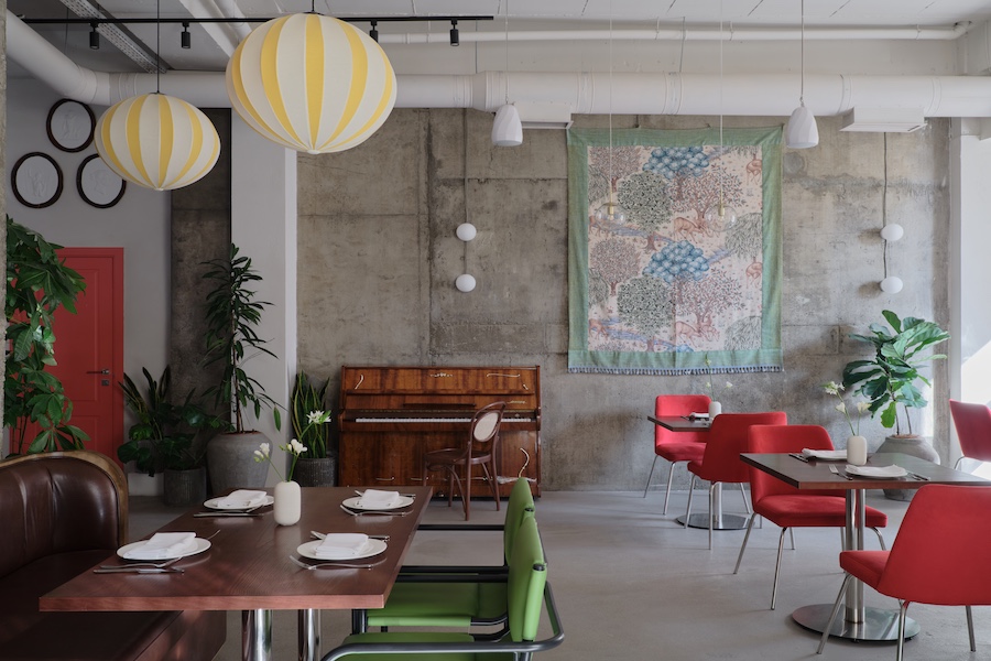 Capito Café Bishkek Kyrgyzstan industrial loft raw concrete walls exposed pipes wall art pink chairs yellow white lantern lights