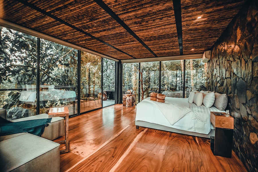 AKEN Hotels & Resorts stone walls bamboo ceiling wood floors floor to ceiling windows private balcony terrace bed