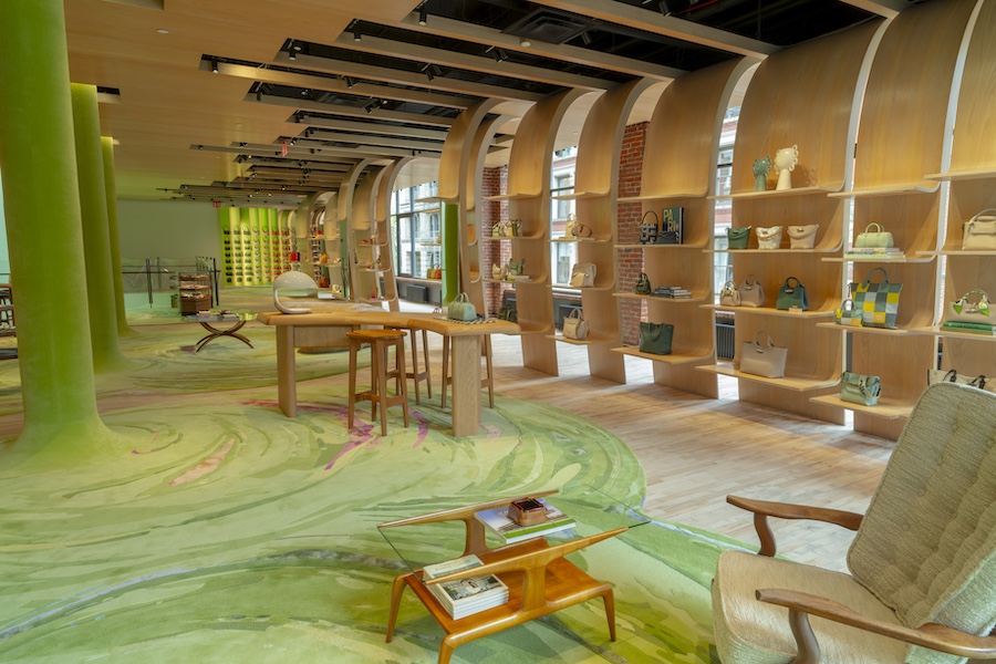 longchamp soho luxury retail store green carpet pillars brown rounded sofa curved wooden shelving