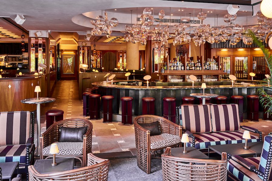 The Dynamo Room new york manhattan steakhouse penn station satellite light fixtures articulating lenses vincent leroy racetrack bar leather stools striped wicker chairs outdoor terrace