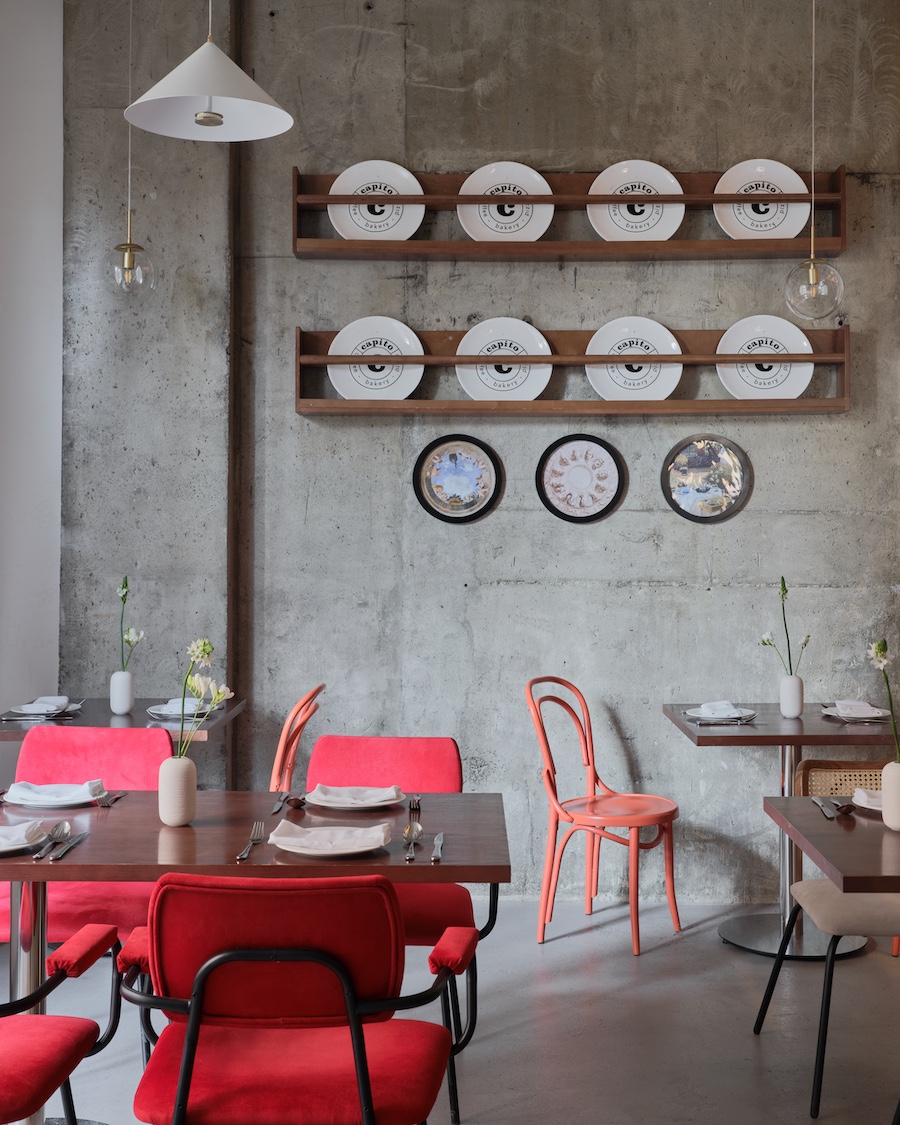 Capito Café Bishkek Kyrgyzstan industrial loft raw concrete walls exposed pipes wall art pink chairs yellow white lantern lights staircase indoor plants pink chairs