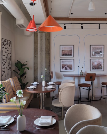 Capito Café Bishkek Kyrgyzstan industrial loft raw concrete walls exposed pipes wall art pink chairs yellow white lantern lights staircase indoor plants orange cone pendant light